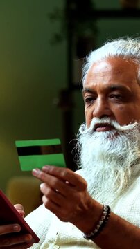 Indian mid age bearded man expressing distress because of online fraud after debit card payment using smartphone at home, stylish mature male feeling frustrated over digital scam and financial theft