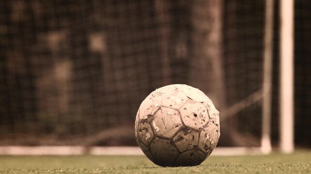 Old worn soccer ball rolling toward goal in Argentine football scene