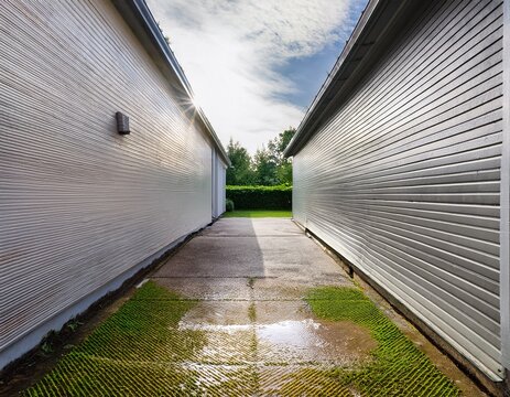 the once stained concrete path of a garage is shown prior to and after cleaning now appearing bright and fresh thanks to pressure washing