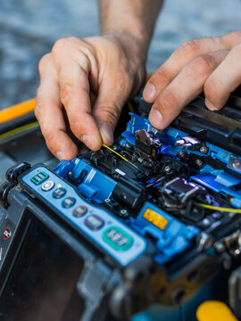 A man using a fiber optic fusion splicer to connect fiber optic cables. Fiber optic cable splicing. Fiber fusion splicer