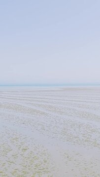 Wide, tranquil views of Binic Beach in Brittany, France, captured during low tide on a clear summer day.