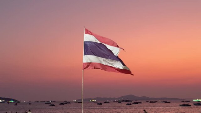 THAILAND : View of Thailand national flag waving in the wind against beautiful orange sunset sky. Concept of country independence, political news and corporate economic success.