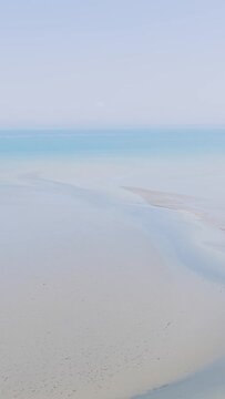 Aerial view of a serene, empty sandy beach and calm turquoise sea at Binic, Brittany, France.