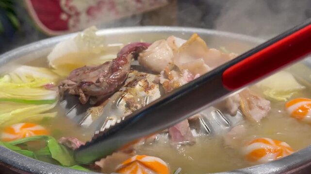 PATTAYA, THAILAND - APRIL 2026 : Close-up shot of sliced pork and beef meat sizzling on Mookata Thai barbecue grill. Local Thai food culture and dining lifestyle.