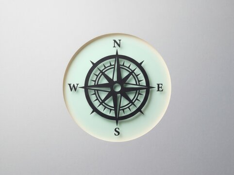 Minimalist compass navigation icon centered on light circular surface
