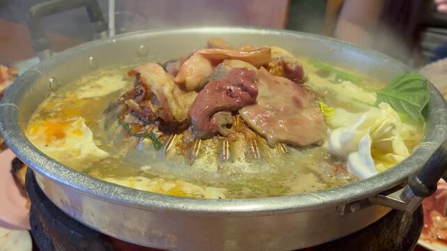 PATTAYA, THAILAND - APRIL 2026 : Close-up shot of sliced pork and beef meat sizzling on Mookata Thai barbecue grill. Local Thai food culture and dining lifestyle.