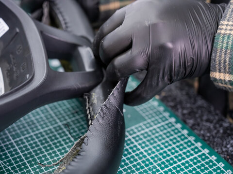 The mechanic changes the cover on the car steering wheel.