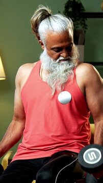 Indian mid age stylish bearded man doing exercise using dumbbell at home, fitness conscious mature male performing weight training workout showing strength, agility determination in modern interior