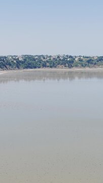 A wide static shot of Binic beach and the coastal town in Brittany, France, during low tide on a clear summer day.