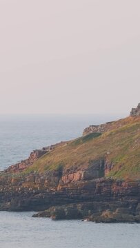 A tranquil summer scene featuring the rugged, rocky coastline of Ilot Saint Michel near Erquy in Brittany, France.
