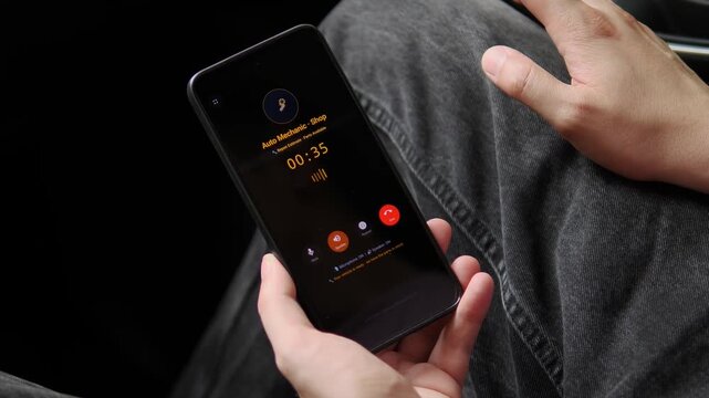A driver speaks with an auto repair shop by smartphone, highlighting remote diagnostics, urgent vehicle support and the growing shift toward mobile automotive service.