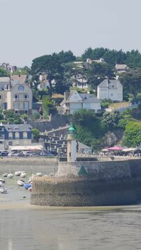 Daytime video clip of the Binic port area in Brittany, France, featuring a small lighthouse on a stone pier in the foreground.