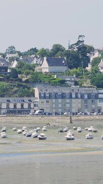 A wide daytime view of Binic Port in Brittany, France, showing numerous small boats resting on the exposed seabed at low tide.