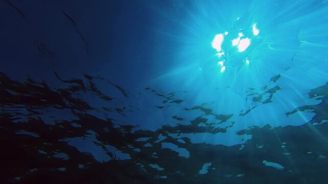 Light shines through water in underwater scene showing waves and ripples at midday