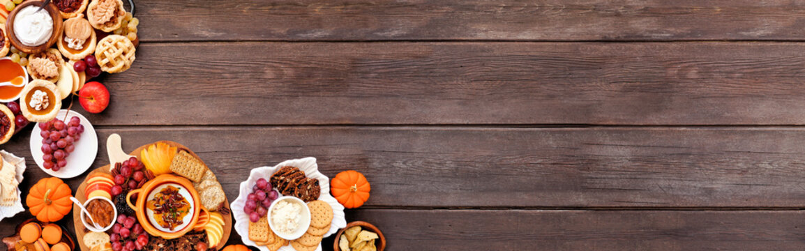 Autumn or Thanksgiving appetizers, sweets and grazing boards. Top view corner border on a dark wood banner background. Pumpkin and apple snacks, charcuterie, pies, desserts.