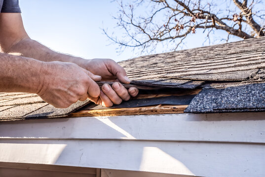 Professional roof repair worker replacing damaged shingles on a residential home