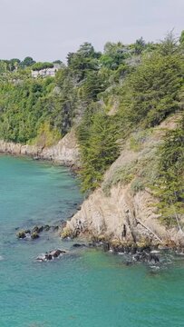 A scenic coastal view of the rocky cliffs and turquoise waters along the shoreline of Binic in Brittany, France.
