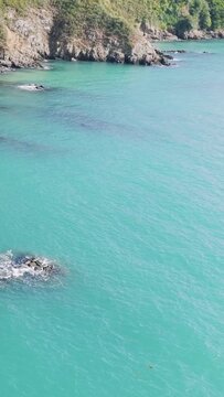Aerial view of rugged coastal cliffs and turquoise water along the shoreline of Binic in Brittany, France.