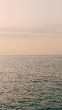 Wide shot of a tranquil sea under a pastel sky at sunset, filmed near Erquy and Ilot Saint Michel in Brittany, France.