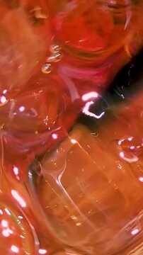 Iced tea beverage with ice cube and straw, orange liquid swirling in a glass, creating cold refreshment, glossy texture, splash movement, and vibrant summer freshness drink concept for advertising.