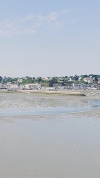 Wide view of Binic beach and town during low tide on a clear summer day in Brittany, France.