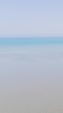 Minimalist video clip showing a tranquil sandy beach and calm blue sea under a clear sky in Binic, Brittany, France.