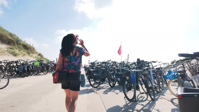 Woman walking past a bicycle parking area near the beach in the Netherlands
