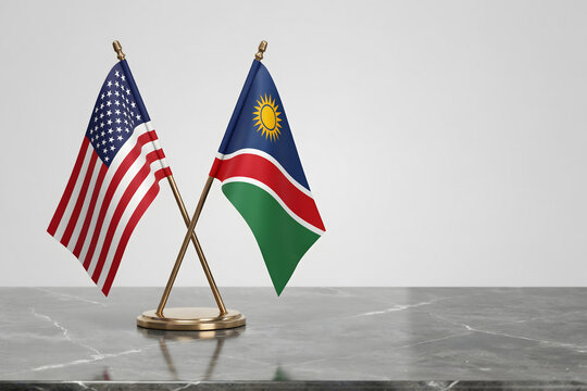 Small crossed table flags of the united states of america and namibia displayed on a grey marble surface against a neutral white wall