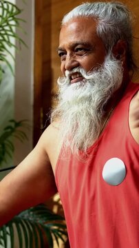 Indian mid age stylish bearded man doing exercise using resistance band at home, fitness conscious mature male showing strength, agility and determination during workout in modern interior