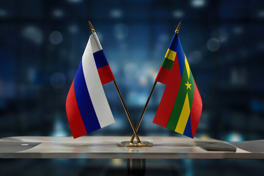 Small desk flags of russia and the central african republic positioned on a white table in a dark blurred office with soft blue ambient light