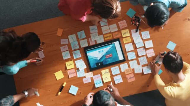 Time lapse of programmer brainstorming and planning about web design while looking at tablet wireframe prototype. Aerial view of skilled developer team talking about digital application. Symposium.