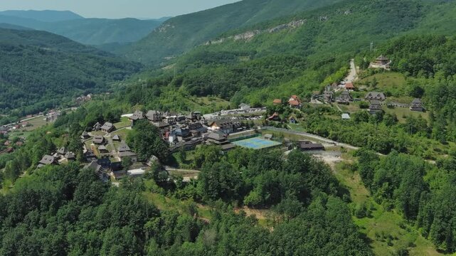 Aerial around view of Drvengrad Kustendorf ethno village on Mokra Gora, Serbia, surrounded by green hills and mountains, 4k