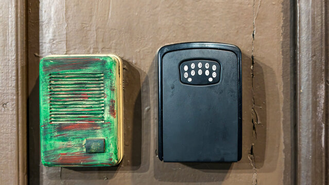 Intercom and key safe box attached to an old wooden door, providing entry management and secure key storage for apartment or rental property access