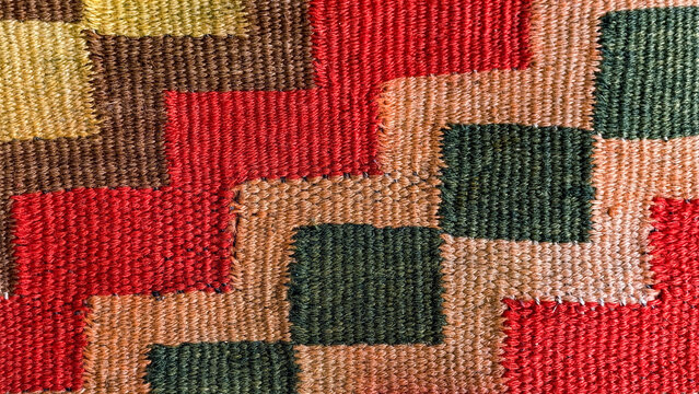 Hand woven textile background showcasing a vibrant. Multicolored geometric pattern with a rich texture. Featuring carefully stitched patches of fabric in an artisanal patchwork design