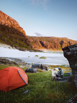 Family camping vacations with tent in northern Norway -  father and daughter travel together outdoor hiking activity, parent and child enjoying sunset mountains view on the beach, explore Finnmark