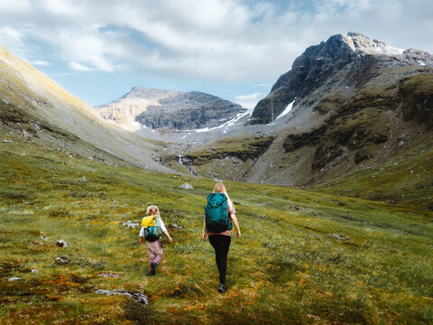 Family travel in Norway - mother and child hiking together, mom and kid on camping vacations tour in Lyngen Alps outdoors summer activity trekking with backpacks through mountain valley