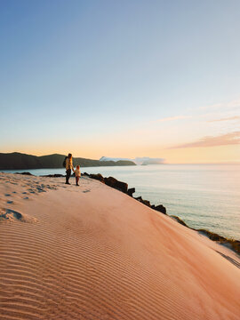 Family travel in Norway vacations mother and kid on hiking trip enjoying sunset sea view standing on sandy mountain, people parent and child explore Finnmark islands active adventure tour outdoor