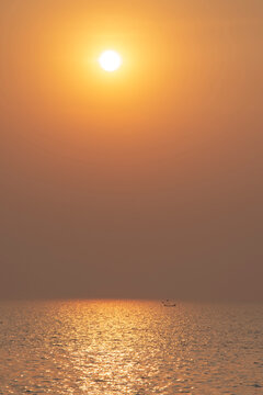 Minimalist golden sunset over calm sea with lonely boat and sky copy space