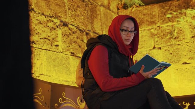 Serene woman deeply immersed in reading time. Peaceful female absorbed in tranquil storytelling moment. Composed woman indulging in calming bedtime story under gentle evening lighting