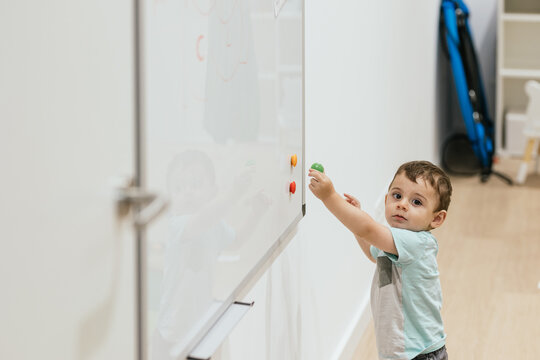 Toddler playing with magnets on whiteboard in optometrist office