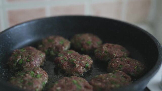 Close-up of traditional Turkish meatballs (k&ouml;fte) sizzling in a black cast iron skillet