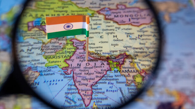 Magnified view of India on map through a magnifying glass for travel exploration and geographical research.
