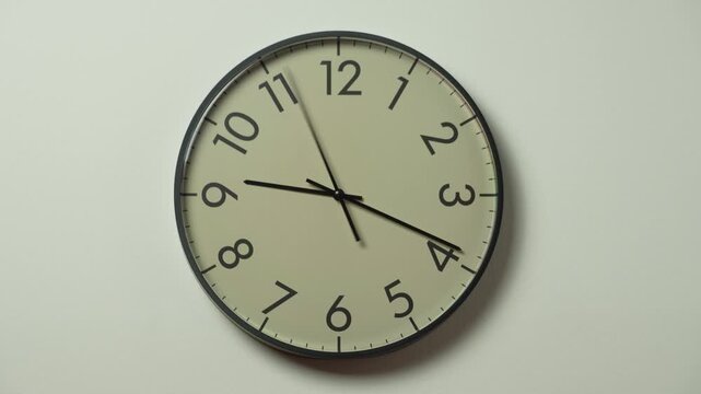 Modern beige wall clock time lapse. Running time pointers. Wall clock showing 9 hours 15 minutes o'clock on a white wall.