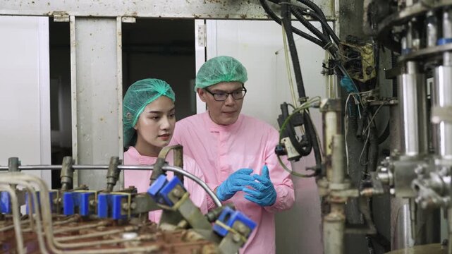 Professional Asian maintenance engineer and technician in food and beverage drink factory in uniform with tablet while talking and discussing machine operation in production line at industry facility.
