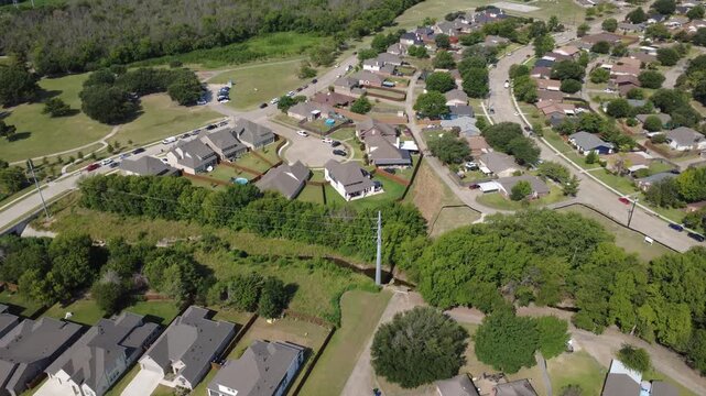 Concrete drainage culvert cuts through Lyons Crest Estates in Dallas Fort Worth suburbs near utility towers. Single family home cul de sacs sit adjacent to greenbelt spaces, Garland, North Texas