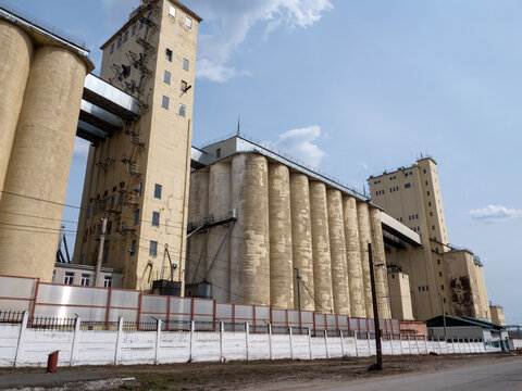 Large concrete grain elevator building against a clear blue sky, industrial agricultural storage facility for grain processing and farming