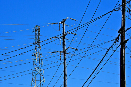 Electrical cable abstract. Old and new high voltage poles pylons with local service wood pole 