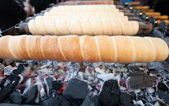 Chimney cake trdelnik bakes above hot charcoal. Traditional Czech trdelnik cake. Trdelnik cake pastry rotates. Prepare fresh chimney cake trdelnik outdoor.