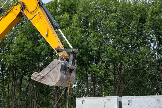 Excavator Bucket Lifting Concrete Blocks at Construction Site
