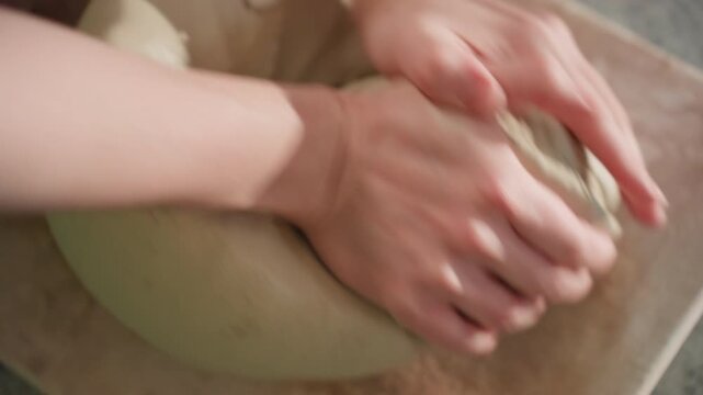 Hands mold clay. Hands press into moist clay forming shape. Detailed view of hands shaping and forming soft wet clay. Close perspective of fingers pressing and molding moist clay into pot